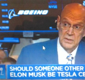 Blurry photo of Willie in a blue suit appearing on television. The news text is cut off, but reads 'Should Someone Other' and 'Elon Musk Be Tesla'
