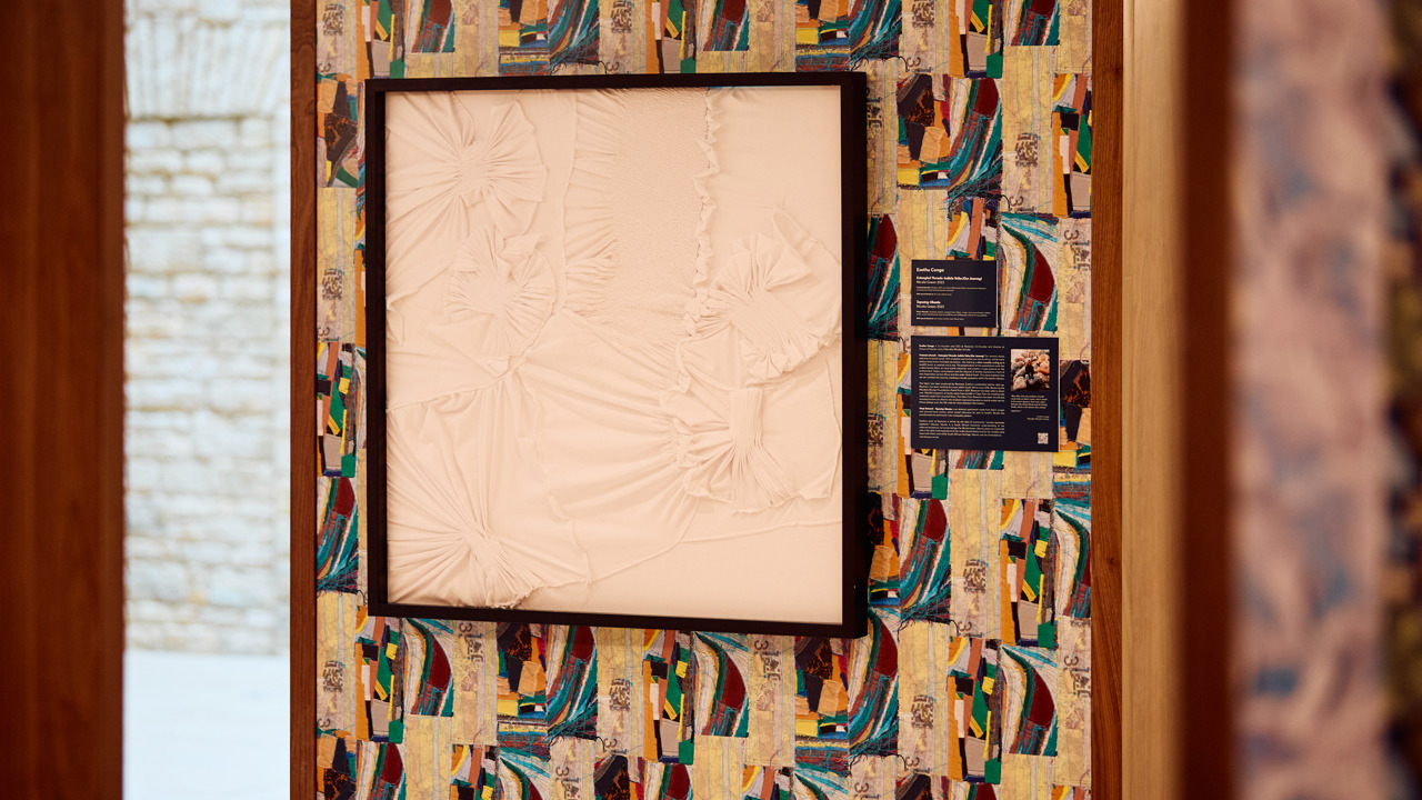 One of the artworks featuring framed white fabric against a colourful patterned wall made up of scraps of fabric