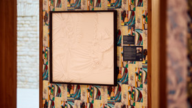 One of the artworks featuring framed white fabric against a colourful patterned wall made up of scraps of fabric