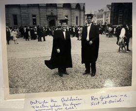 A black-and-white picture of Bob and his Scottish friend Ron Graham of Oriel College dressed in gowns and standing in front of the Sheldonian Theatre with a crowd of similarly-dressed students in the background