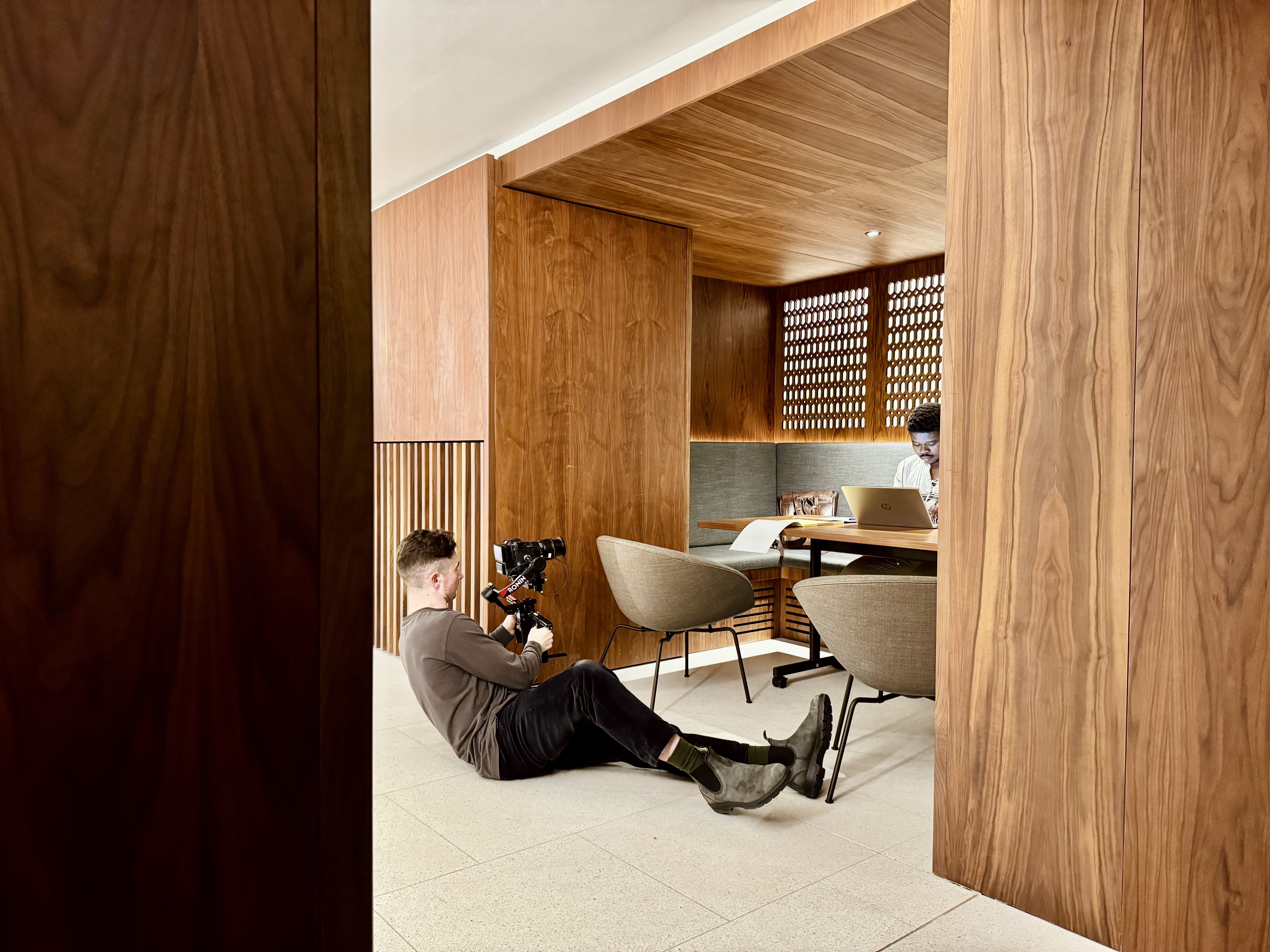Person being filmed while working on a laptop and sitting in a nook in the Conference Foyer.