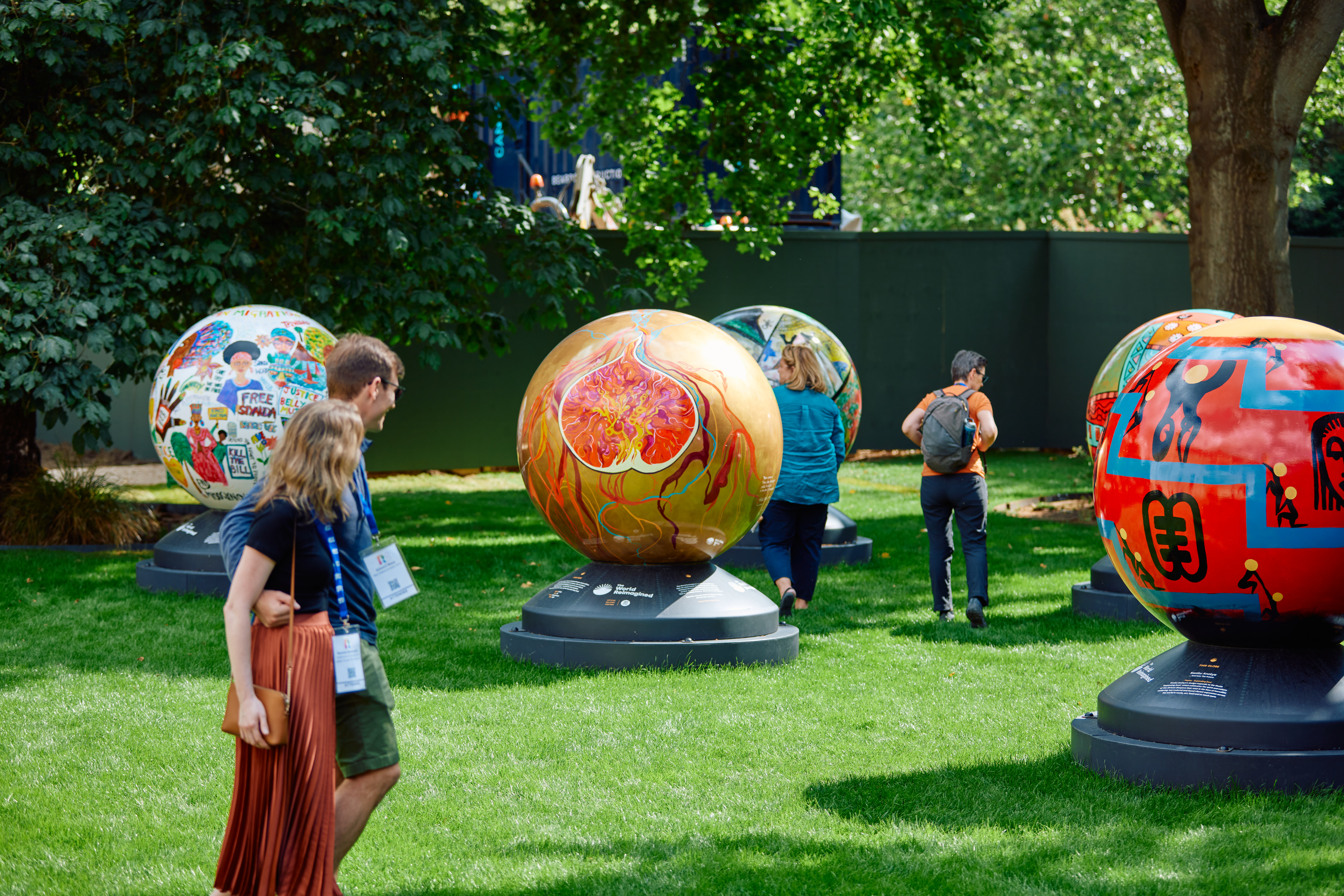 Globes arranged across the lawn of Rhodes House garden as a couple admire them from a distance