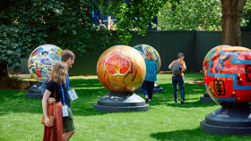 Globes arranged across the lawn of Rhodes House garden as a couple admire them from a distance