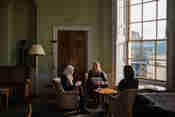 Three Scholars sitting in coversation by a sash window