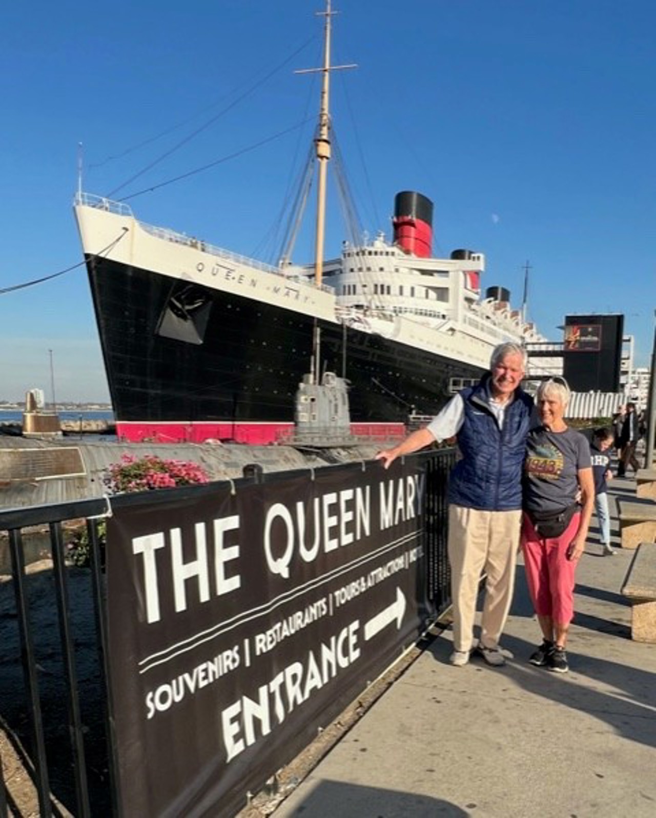 Couple stood in front of large ship.