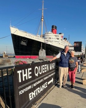 Couple stood in front of large ship.