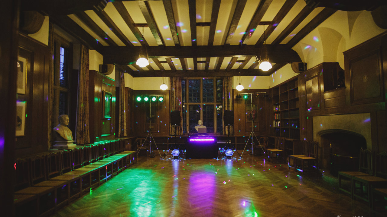 Beit Room set up for a disco with disco balls, lighting, and a DJ desk and speakers at the far end. Photo courtesy of Gemma Williams Photography.