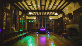 Beit Room set up for a disco with disco balls, lighting, and a DJ desk and speakers at the far end. Photo courtesy of Gemma Williams Photography.