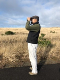 Greg stood with binoculars looking out to the coast.