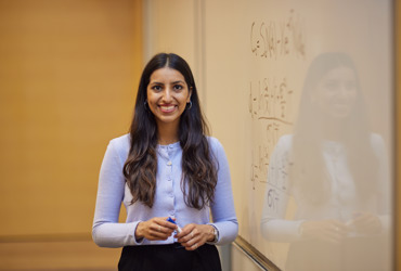 A Scholars standing in front of a whiteboard covered in calculations
