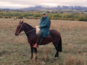 Peter on a field, sitting on top of a horse.