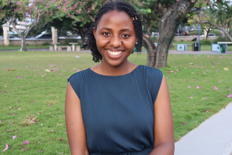 Gloria smiling into the camera, with a park behind her
