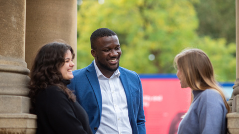 An image of three students standing and talking outside the Rhodes House building