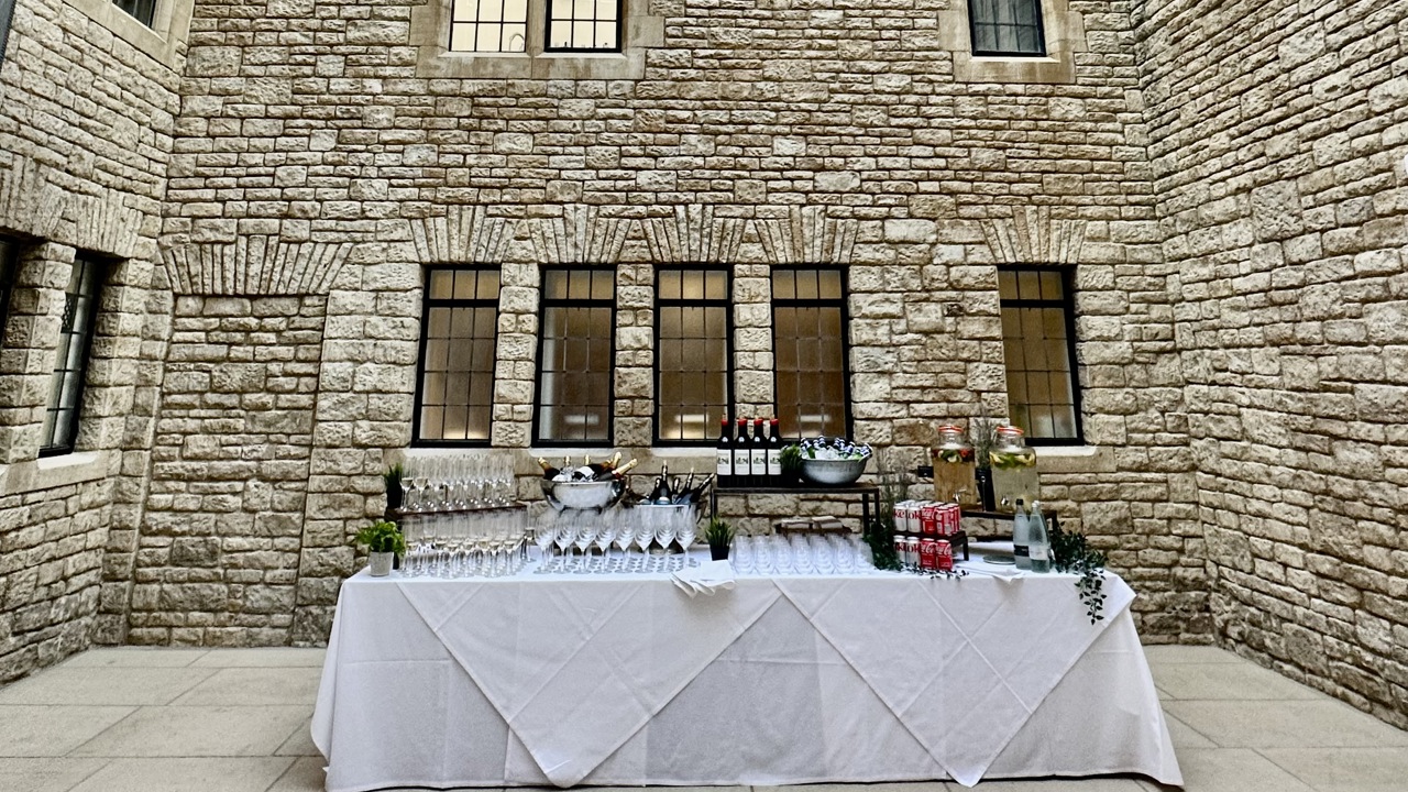 Lightwell with table set up for a drinks reception and blue skies visible through the glass ceiling.