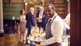 Waiter with tray of sparkling wine welcoming guests into the Reception Room.
