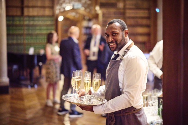 Waiter with tray of sparkling wine welcoming guests into the Reception Room.