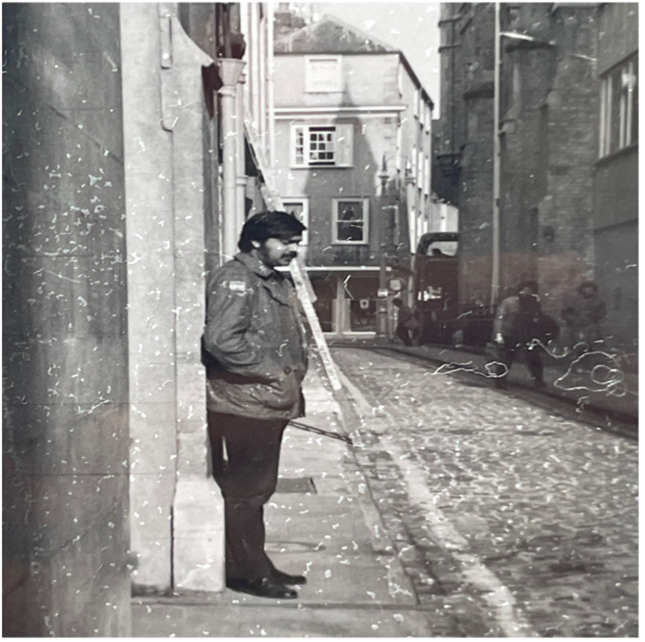 A black-and-white picture of Jahar leaning against a wall in a street in Oxford