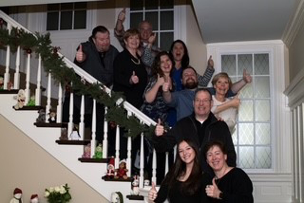 A group of people standing on a white staircase. They are all smiling.