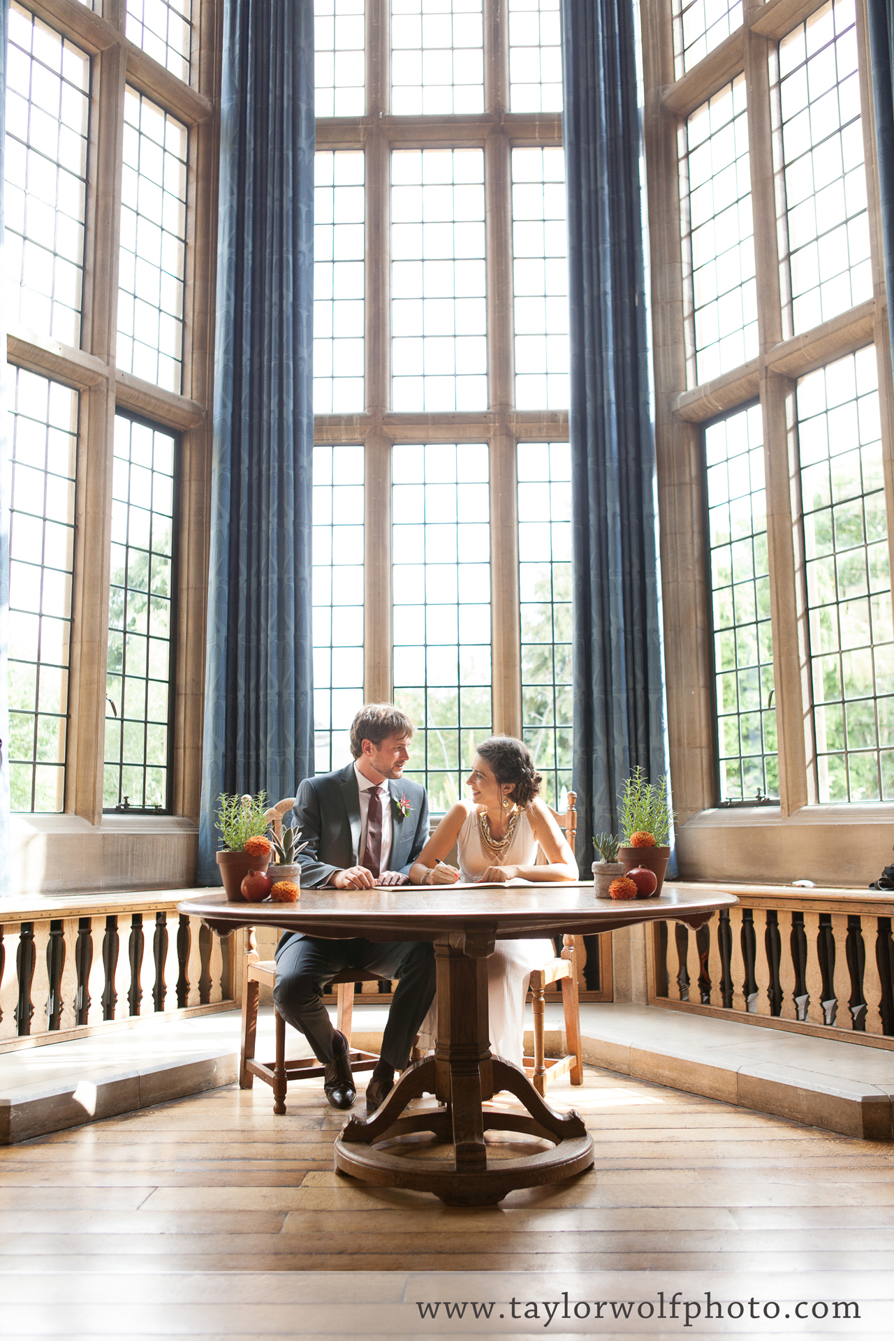 Bride and groom seated at the round table in the McCall MacBain Hall bay window.