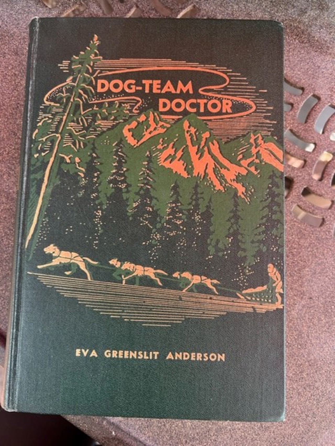 A book with the title 'Dog-team doctor'. The cover shows silhouettes of dogs walking a path. The writer is 'Eva Greenslit Anderson'.
