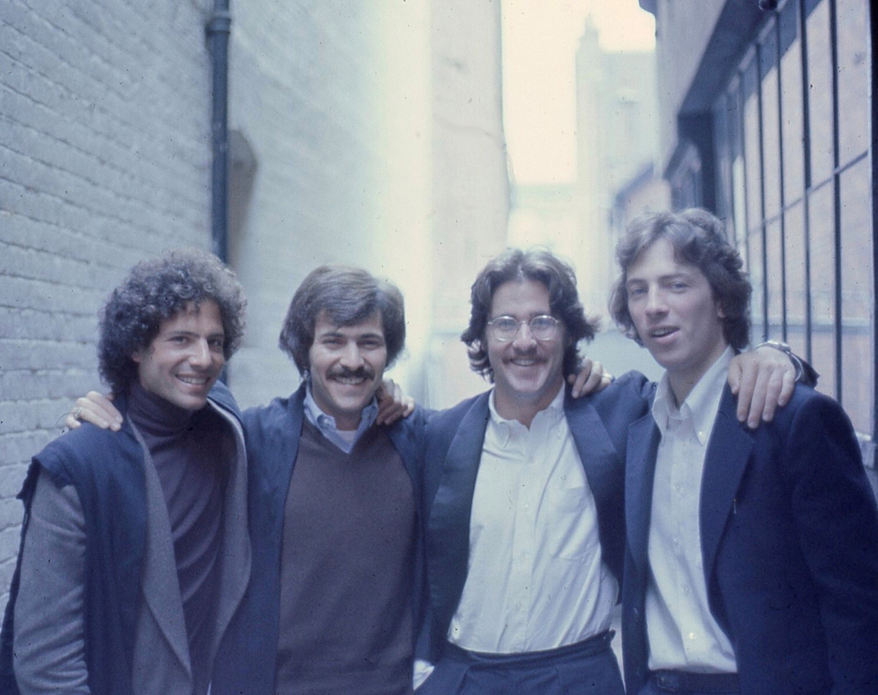 Vintage photo of four friends standing with arms around each other.