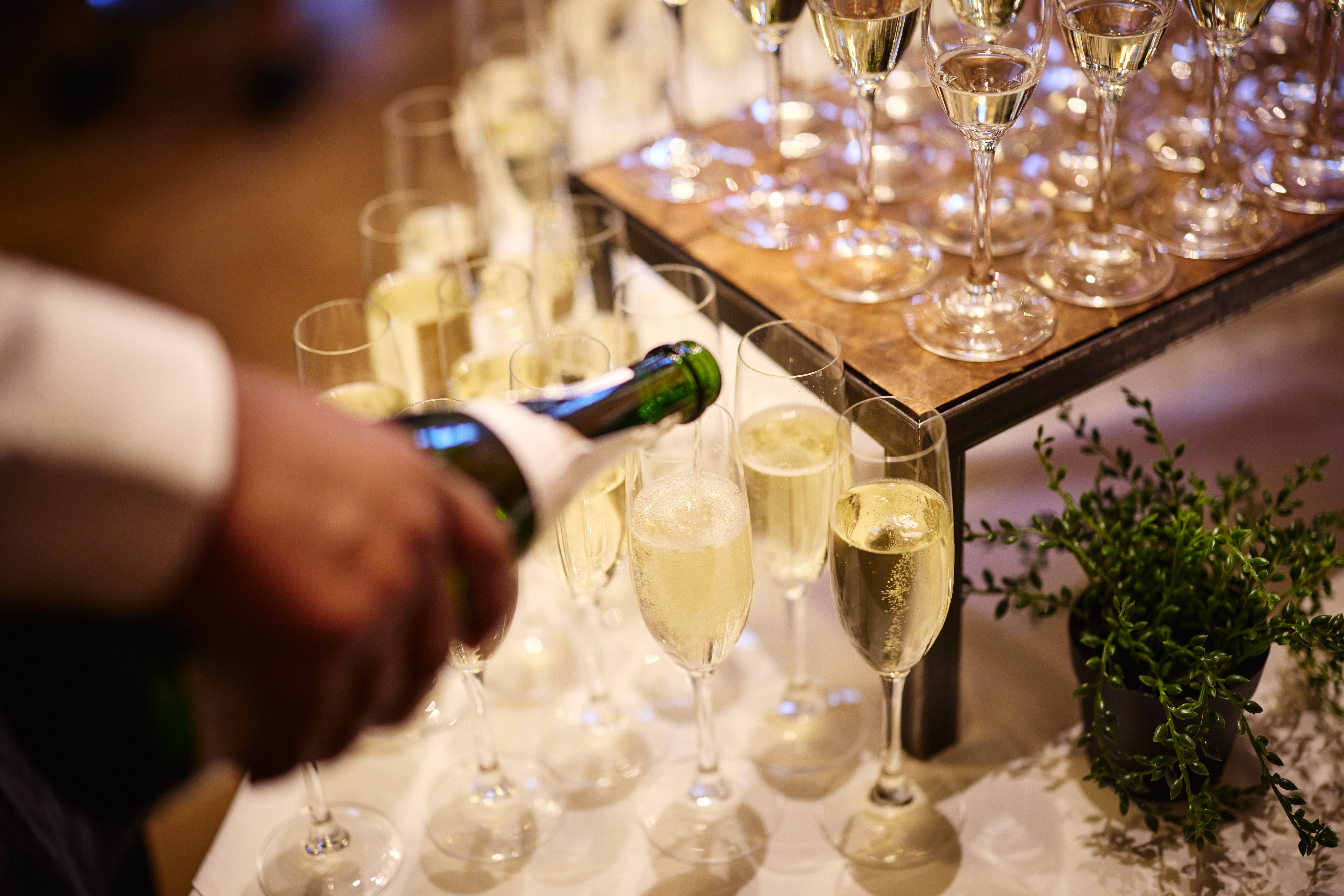 Sparkling wine being poured into glasses set up on a service table.