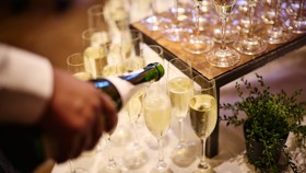 Sparkling wine being poured into glasses set up on a service table.