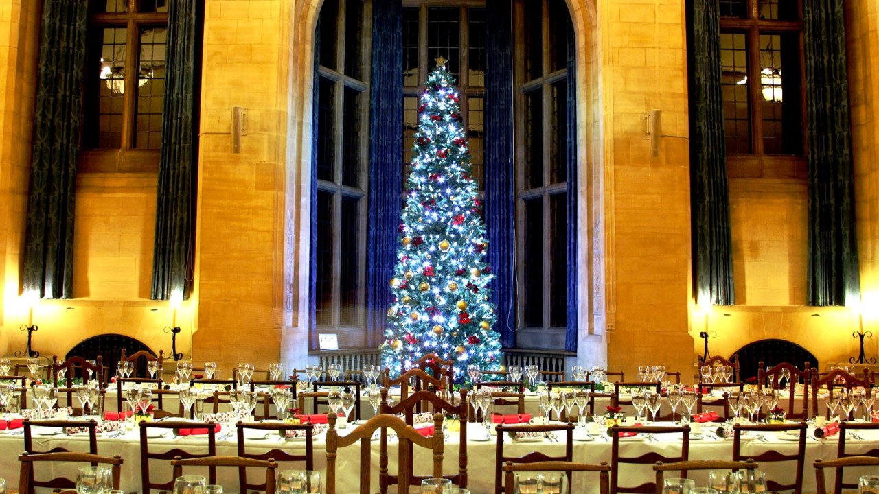 McCall MacBain Hall set up for Christmas with a large Christmas tree in the bay window and tables laid for dinner.