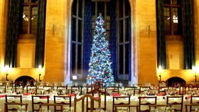 McCall MacBain Hall set up for Christmas with a large Christmas tree in the bay window and tables laid for dinner.