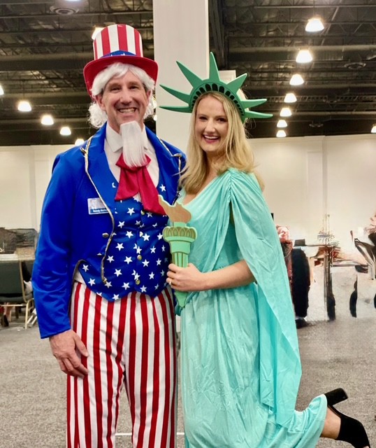 Randy stands to the left of his daughter Harriet, both are in costume. Harriet is dressed as the statue of liberty, and Randy is dressed as Uncle Sam.