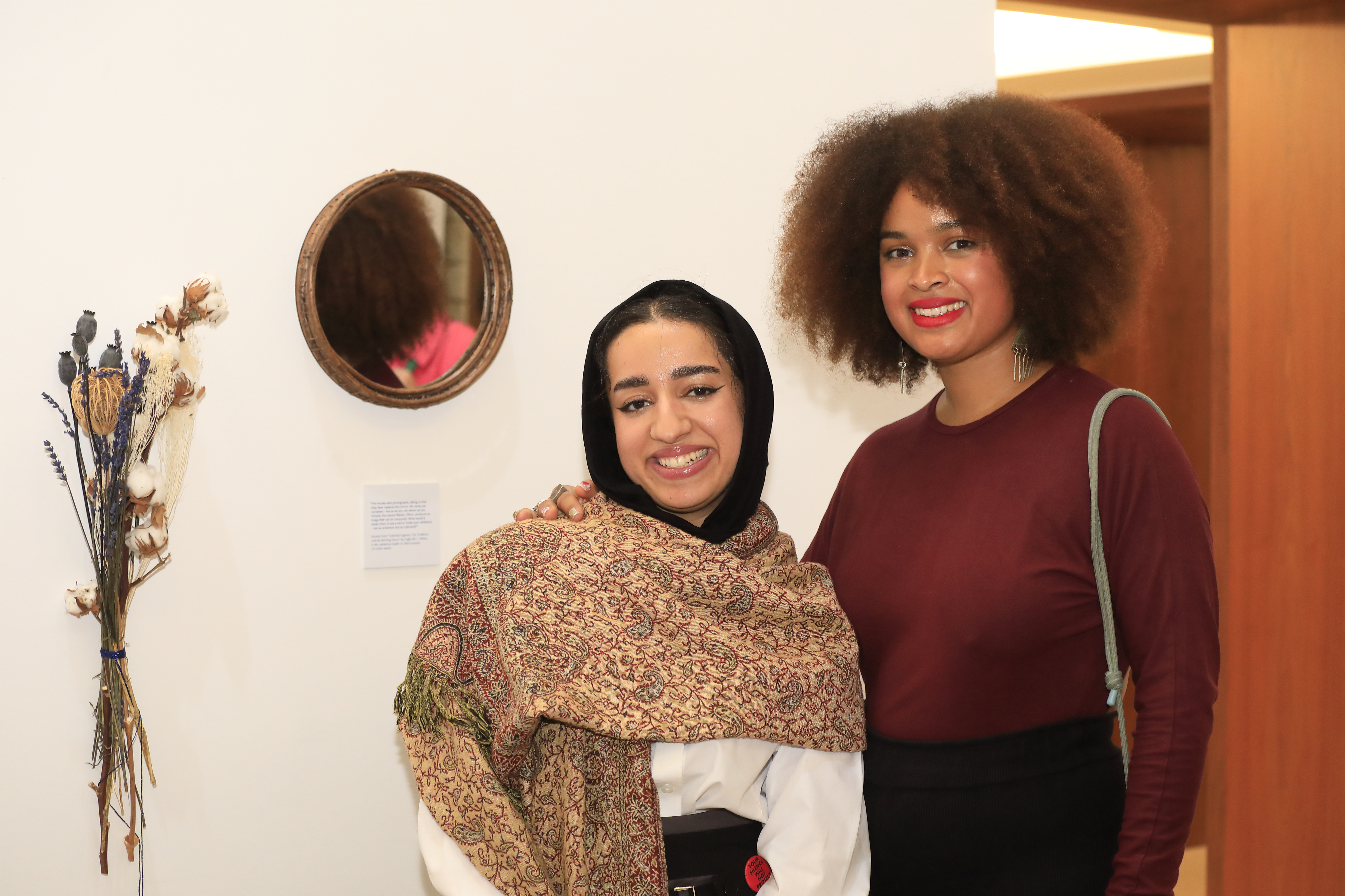Maitha AlSuwaidi and Rebecca Korang in front of a mirror and flowers