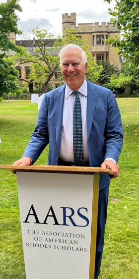 Ron smiling, standing before an AARS podium on a green lawn.