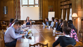 Conference breakout group seated in the Rhodes House Beit Room at a boardroom table.