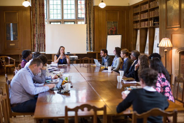 Conference breakout group seated in the Rhodes House Beit Room at a boardroom table.