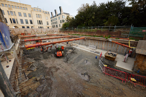 An image of a construction site with vehicles and scaffolding. The workers are excavating the Rhodes House Residential Courtyard.