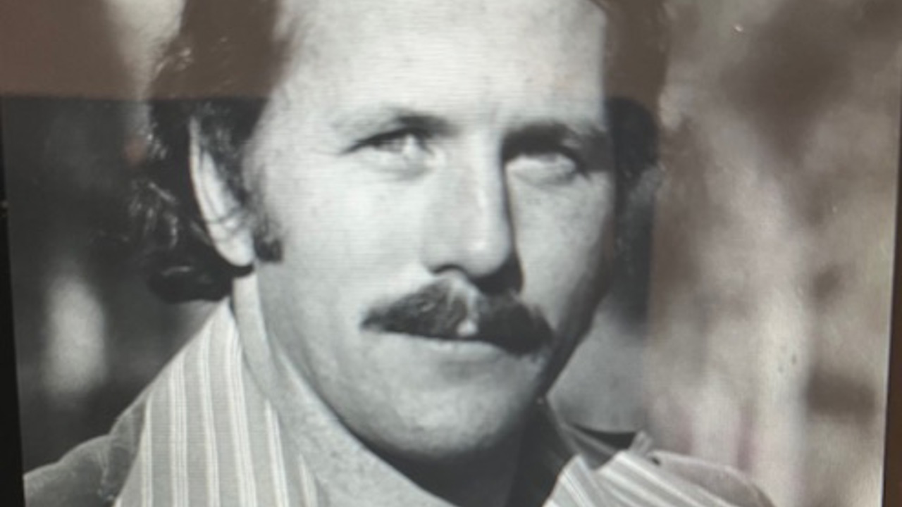 A black-and-white portrait of Peter. He's wearing a jacket over a striped shirt with large collars.