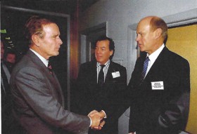Willie in a suit, shaking hands with George W Bush. There is another suited man stood between them.