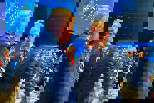 President Duda stands with his arm on a chair while talking with President Trump at a NATO conference