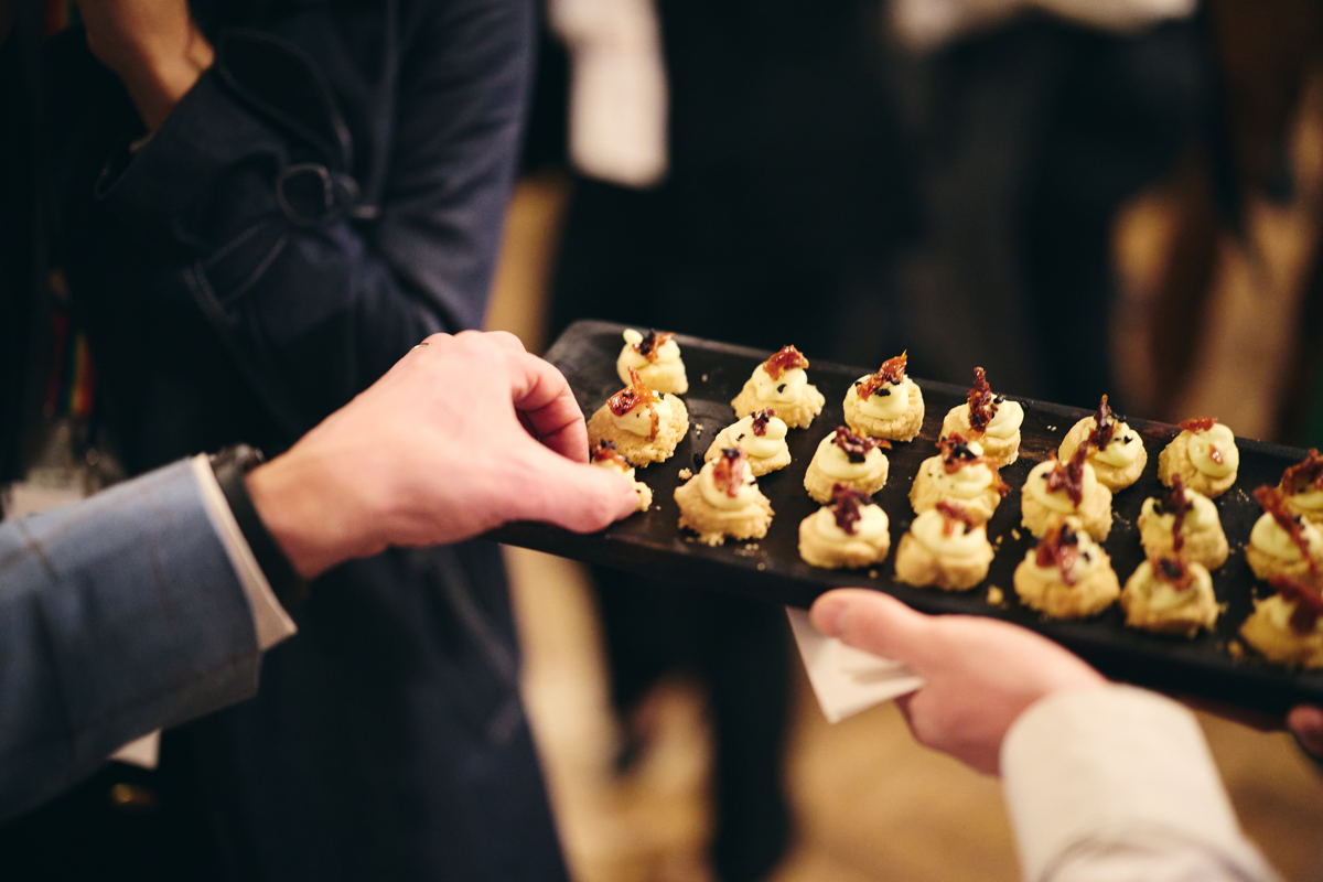 Close up view of a hand taking a canape from a tray.
