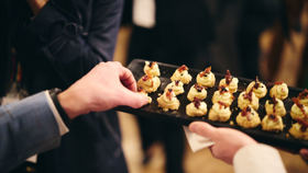 Close up view of a hand taking a canape from a tray.