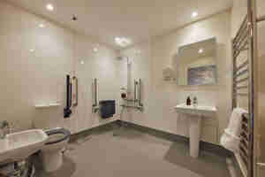 An Accessible Bathroom With A Shower Toilet And Sink