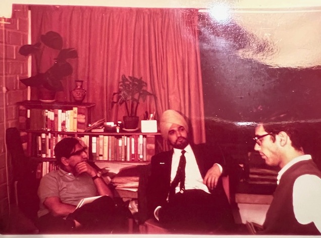 Richard sat with two other friends on sofas, red tinted photo.