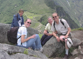 Rob and family sat on rocks on top of Machu Pitchu, smiling, wearing backpacks.