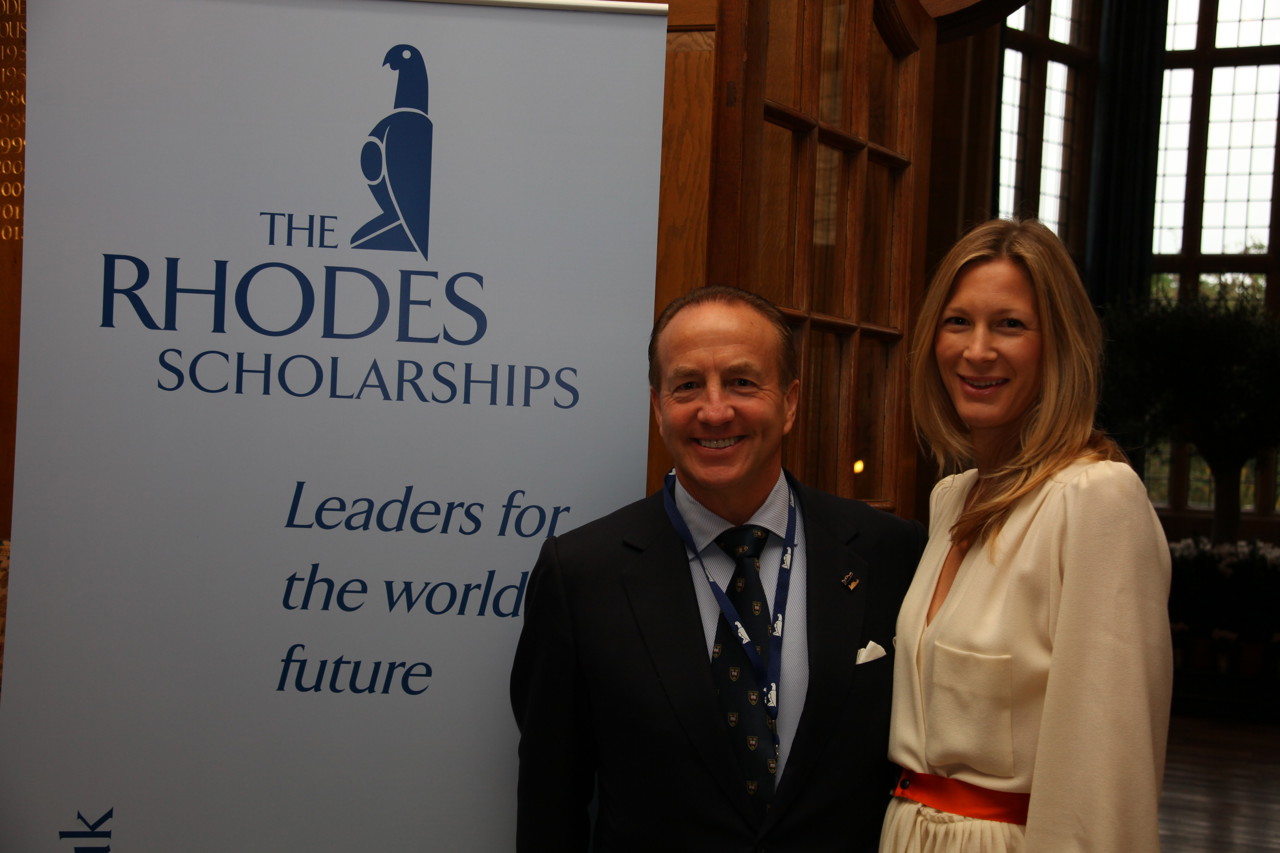 John and Marcy stood to the right hand side of a banner which reads 'The Rhodes Scholarships Leaders for the worlds future'