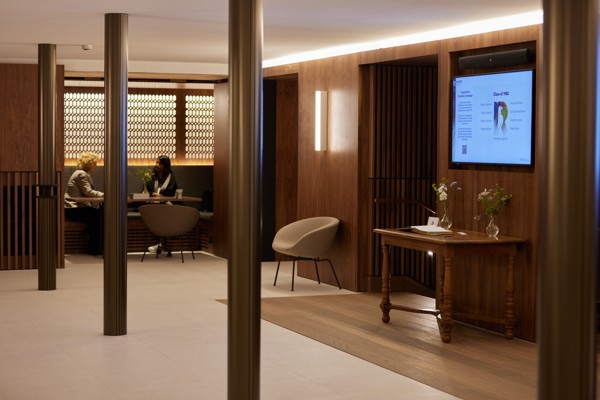 Conference Foyer nooks with tables and chairs. Two guests are seated in the nook and a display screen is shown in the foreground.
