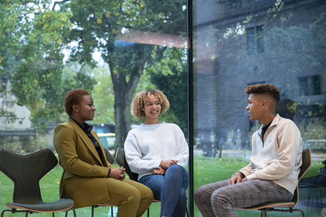 3 Scholars sat speaking in the Glass Pavilion at Rhodes House