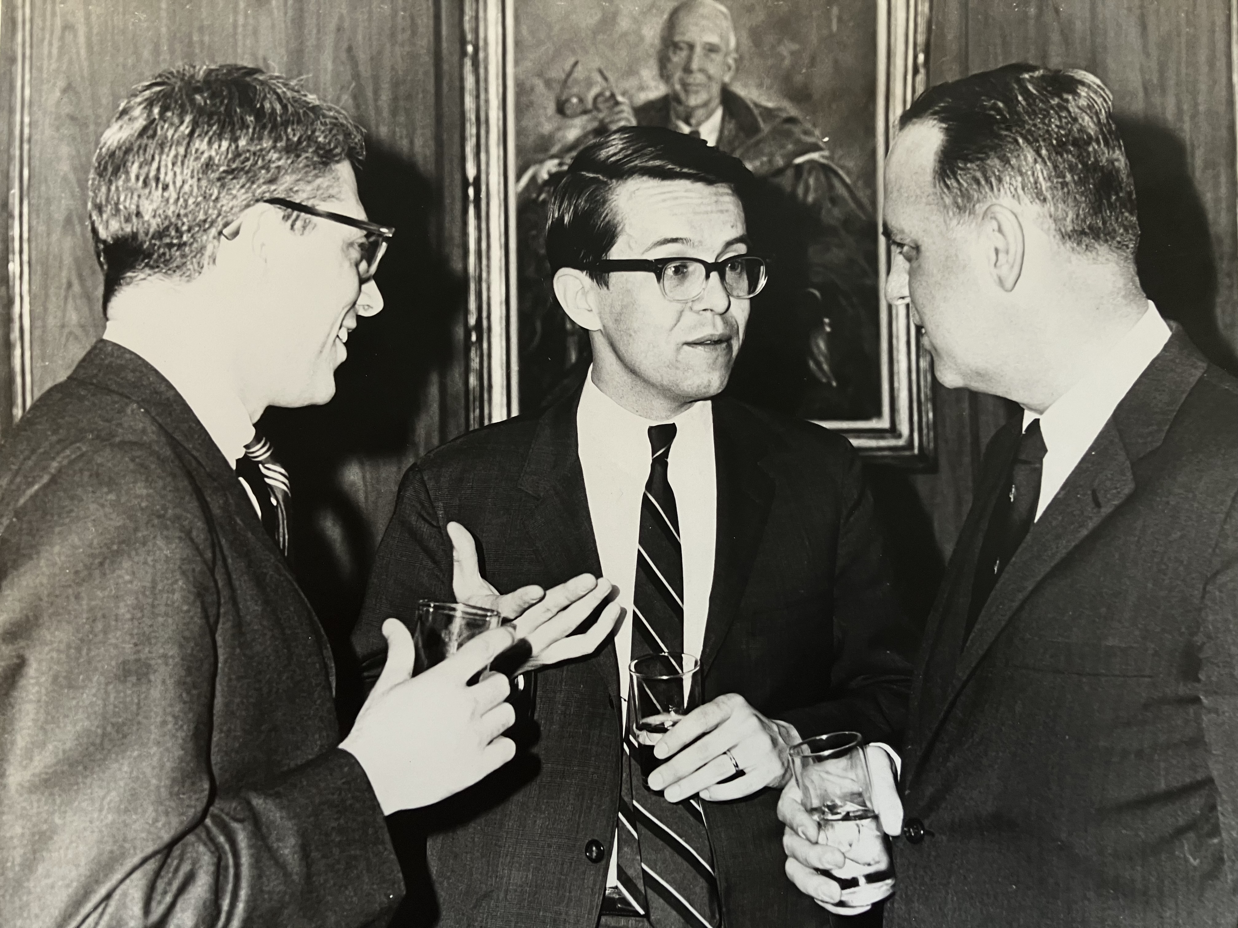 The picture shows Peter with two other men. They are all in suits and are talking to each other.