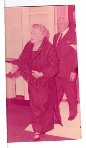 A pink-tinted picture showing an old woman in a dress