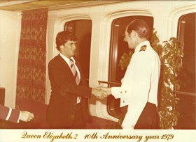A sepia-tinted picture that shows John shaking hands with a ship captain