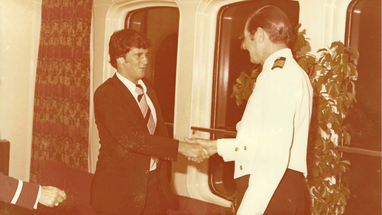 A sepia-tinted picture that shows John shaking hands with a ship captain